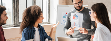 Team of professionals discussing digital marketing strategies for restaurants and assisted living facilities, with one person presenting a chart in an office setting.